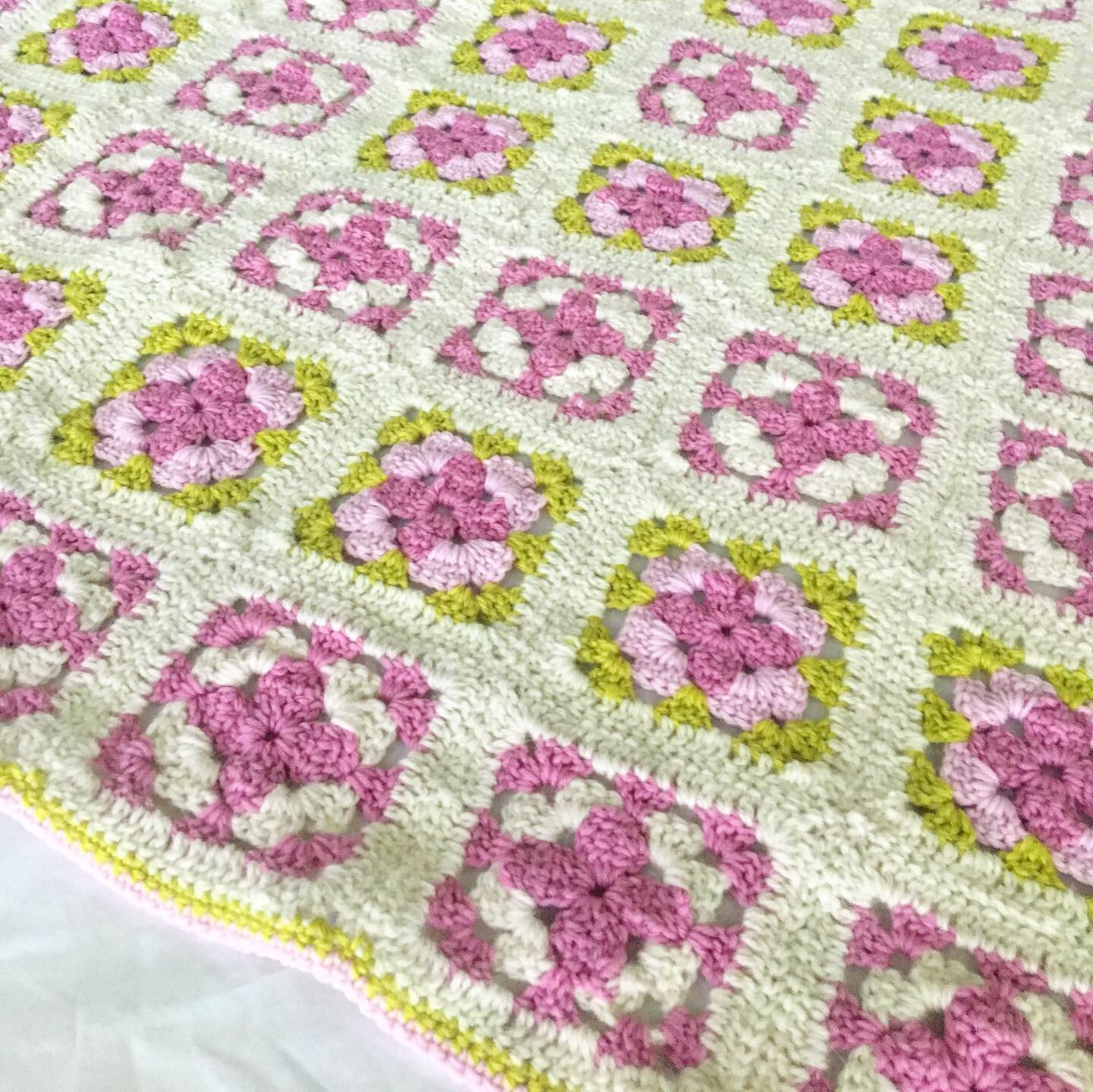 white, purple, and greeny crocheted granny square blanket