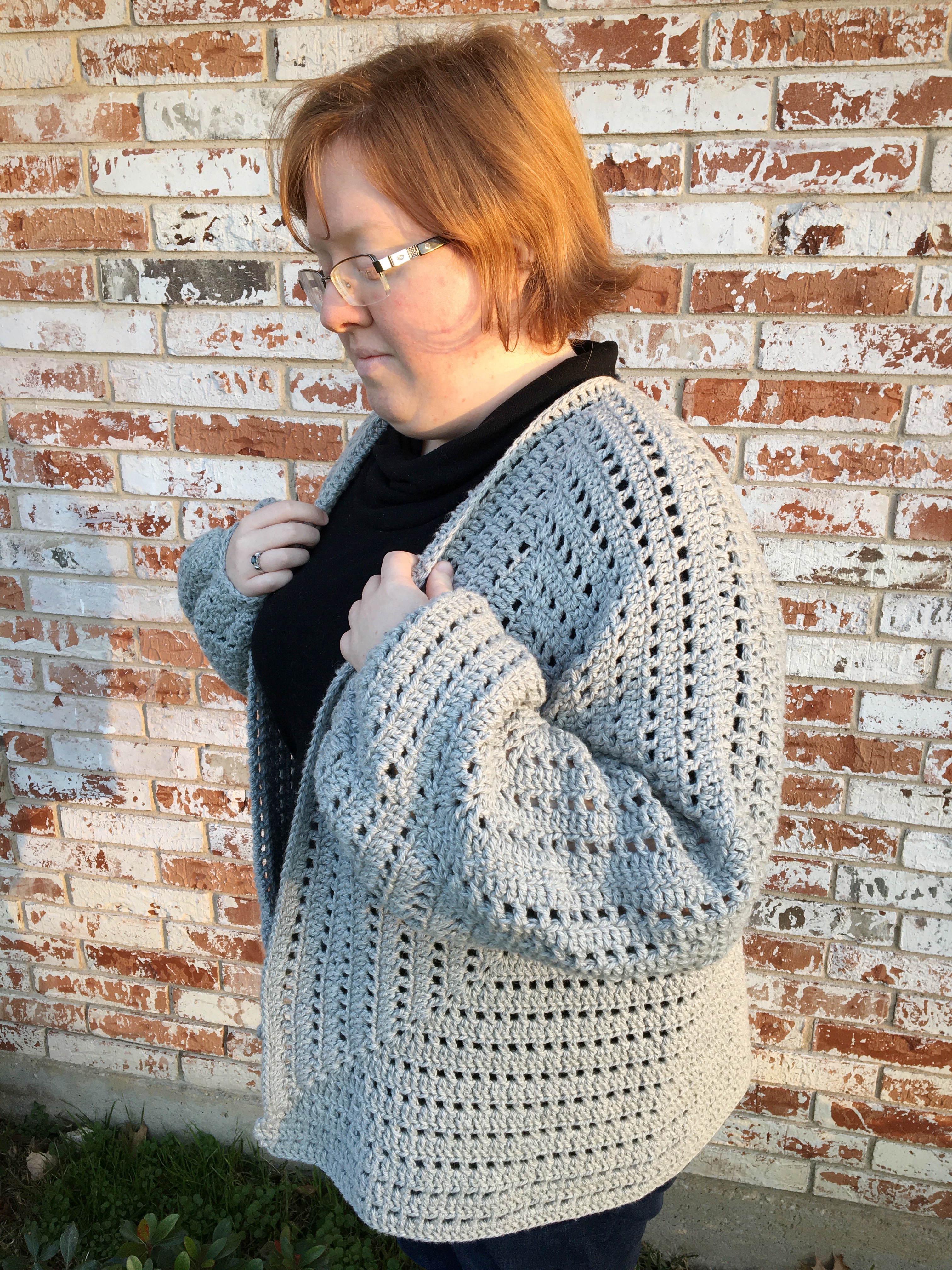 grey crocheted cardigan worn by a red haired woman