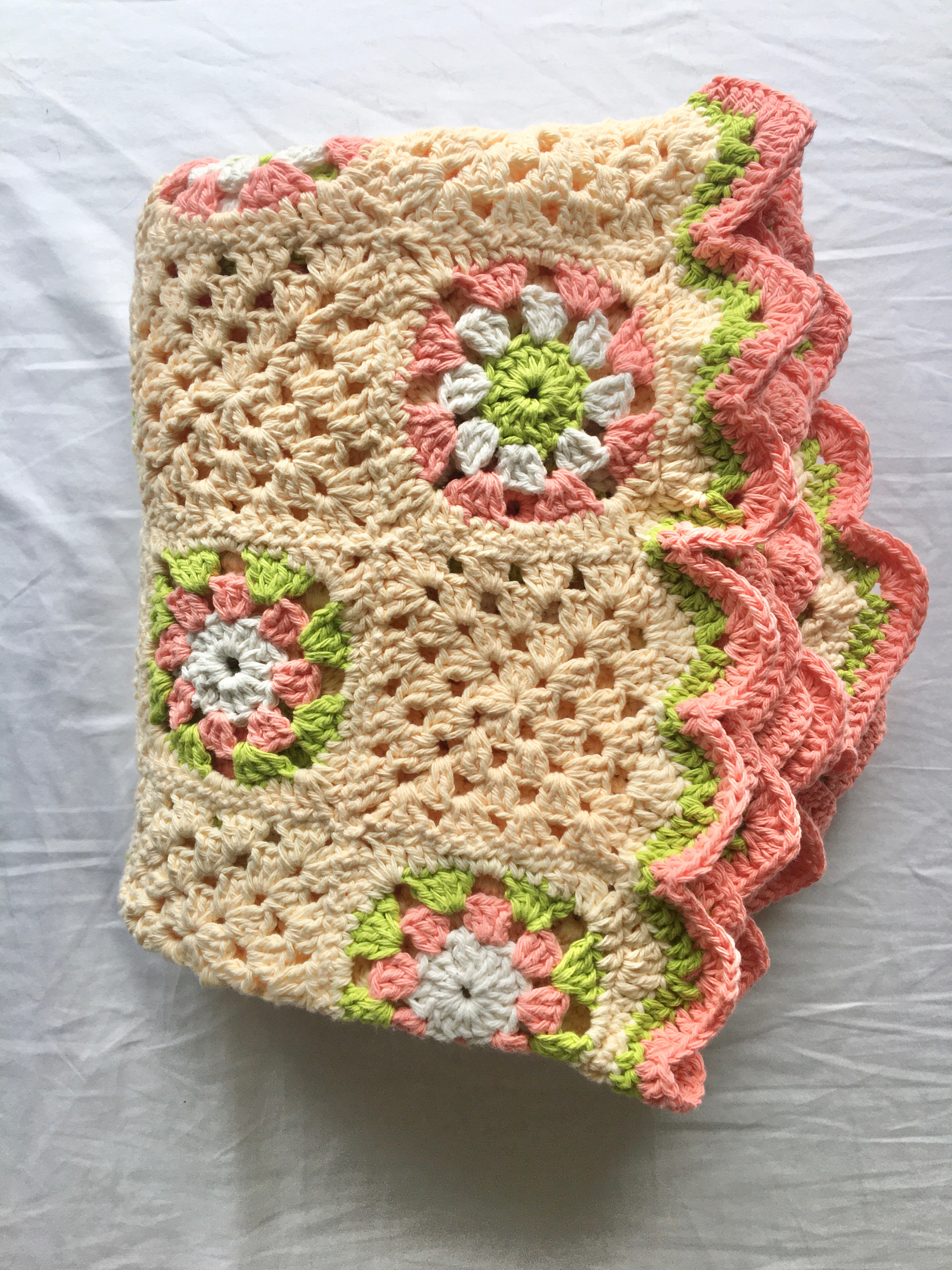 yellow, pink, and green crocheted granny square blanket