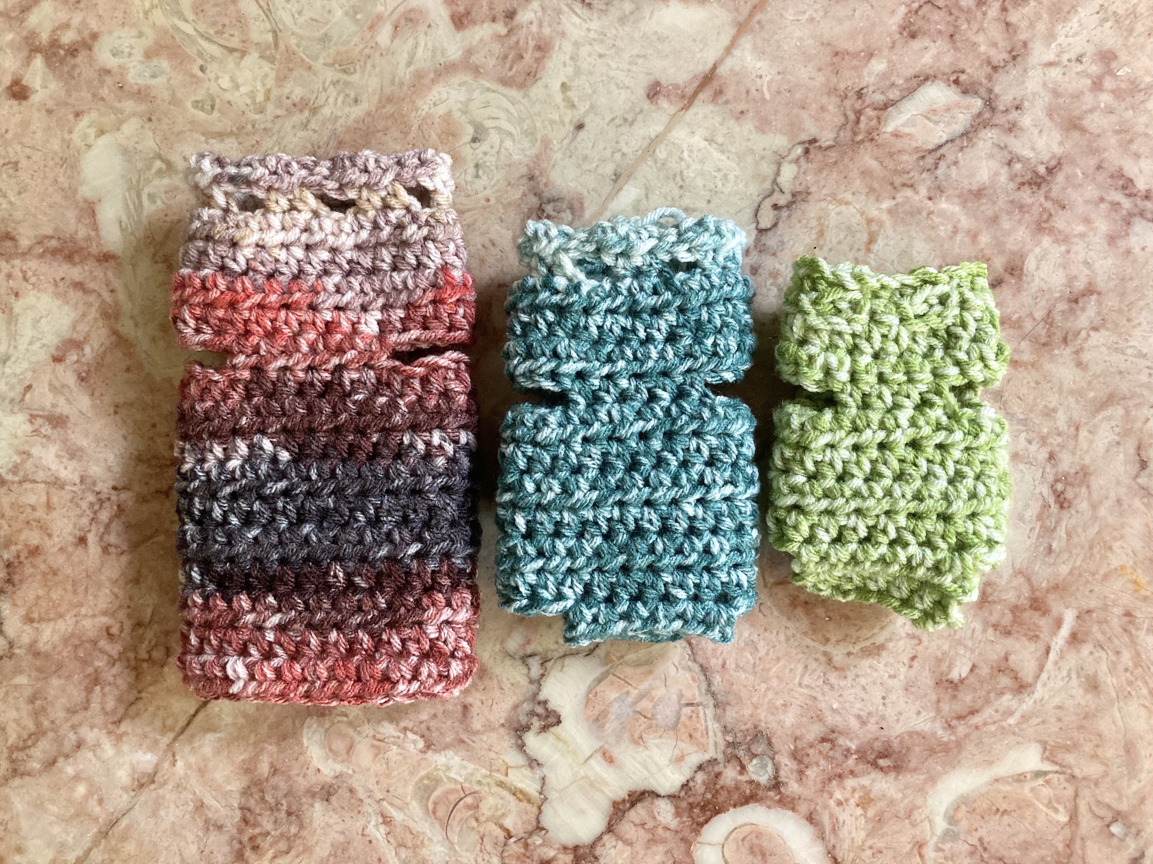 three stacks of small knitted kitten sweaters in large, medium, and small sizes